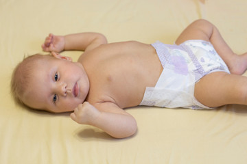 a small infant with blond hair lies on a yellow blanket