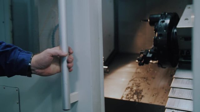 worker open the door of cnc machine at workshop.
