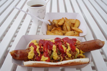 Hot-dog with mustard, ketchup, pickles, onions, fries and coffee