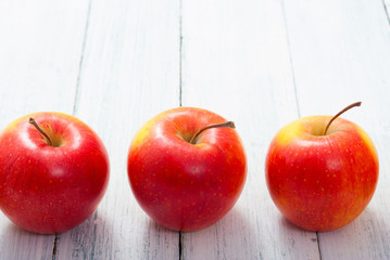apple fruits in a row, white wooden table background
