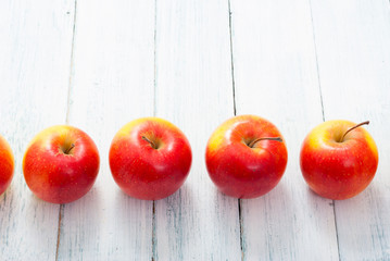 apple fruits in a row, white wooden table background