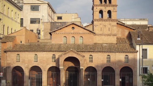 Basilica of Saint Mary in Cosmedin with Mouth of Truth or Bocca della Verita. Unrecognizable people and cars passing by. Camera moving up in slow motion