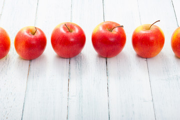 apple fruits in a row, white wooden table background