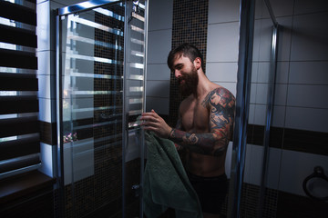 Fototapeta na wymiar A bearded guy with a tattoo in the shower.Sexy guy in the shower.