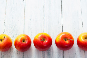 apple fruits in a row, white wooden table background