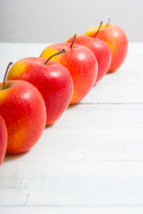 apple fruits in a row, white wooden table background