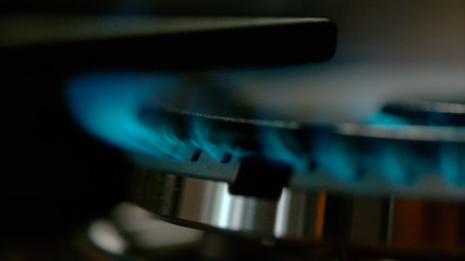 Fototapeta na wymiar MACRO: Blue fire burning out of a gas burner on a large modern metal stove.