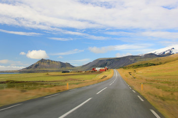 Road with farm and mountains in background (Iceland)