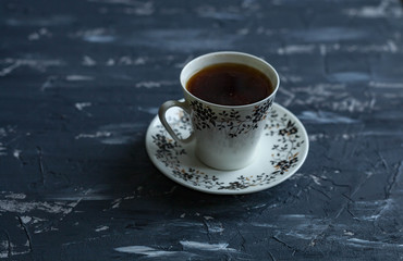White cup with black coffee on a dark background