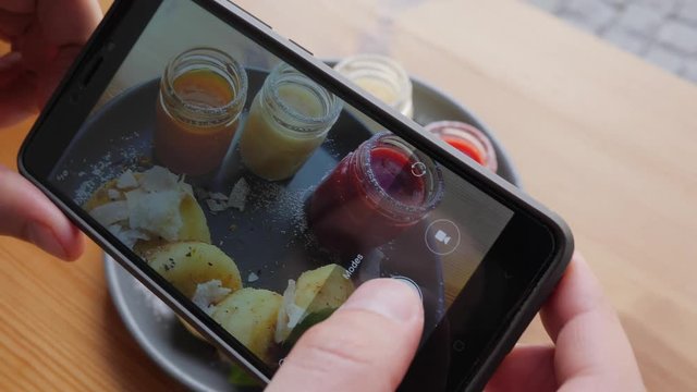 Food photo man takes pictures via smart phone of dish in cafe bistro during breakfast for social media