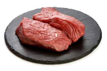 Fresh raw beef steaks on slate shale plate, sliced meat, close-up, isolated on white background
