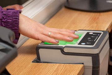 The process of scanning fingerprints during the check at border crossing. Female hand puts fingers to the fingerprint scanner. Identity verification and border control, immigration concept