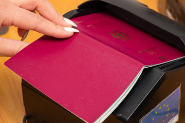 The process of scanning a German biometric passport to register the fact of crossing the state border. Female hand puts a passport to the scanning device. Concept of overseas travel, immigration