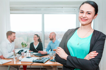 portrait of a beautiful woman in office with colleagues on background