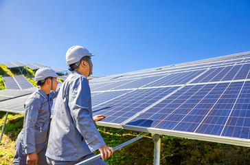 Two Asian engineers are testing the solar photovoltaic base at the top of the mountain