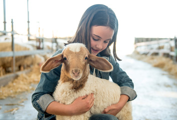 Cute girl poses with a lamb in her arms