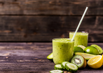 Green smoothie made by avocado, lemon and kiwi on natural wooden background.