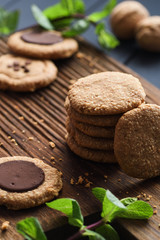 Healthy sugar free gluten free vegetarian sweets. Peanut butter cookies with dark chocolate drops served with raw mint on dark oak board
