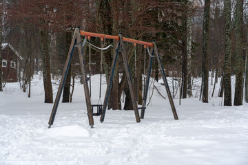 Empty swings in the childrens playground on a winter day with snow, Helsinki Finland