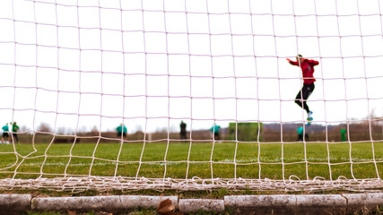 Football goal net and players warming up