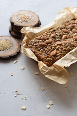 Homemade gluten free sugar free vegetarian snack. Oatmeal bread baked in paper served with whole almonds, flax and amaranth seeds on wood slabs on white background