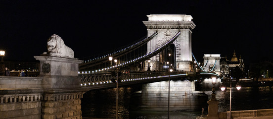 Naklejka premium Panoramic view of the Chain Bridge at night in Budapest with the lions in the foreground, Hungary
