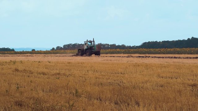A farmer on a tractor handles the field The farmer on the tractor handles field farm is hard work on the ground 