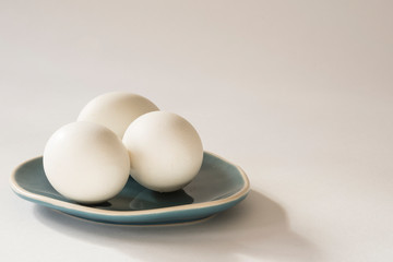 three white eggs on blue plate. White background, space for text