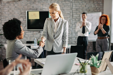 Happy businesswomen shaking hands after successful agreement in the office.