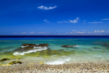Sea background. Picturesque summer beach, pebbles in the surf line on a beautiful turquoise sea, Rhodes, Greece,  excursions, travel, recreation and vacation. 