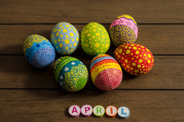 April made from colorful letters and colorful decorated easter eggs on wooden background