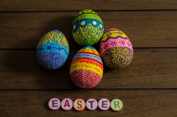 Easter made from colorful letters and colorful decorated easter eggs on wooden background