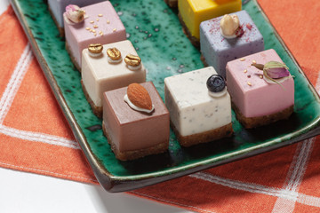 Dessert. Assorted fruit pastries made from natural products on a beautiful, green plate on a red napkin on the background. Cakes with fresh berries and nuts.