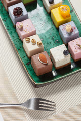 Dessert.  Assorted fruit pastries made from natural products on a beautiful, green plate on a white background. Cakes with fresh berries and nuts.