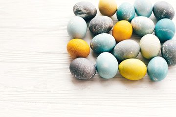Happy Easter greeting card. Stylish Easter eggs on white wooden background, copy space. Modern colorful easter eggs painted with natural organic dye. Easter creative pattern