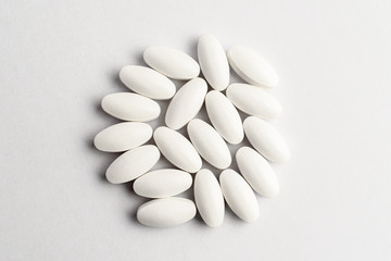 Close up of a group of white pills on white background, beautifully arranged on a table