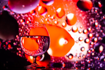 transparent glasses with water with oily drops on colorful background 
