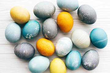 Fototapeta na wymiar Stylish Easter eggs composition, flat lay on white wooden background. Modern colorful easter eggs painted with natural dye. Happy Easter greeting card. Easter pattern