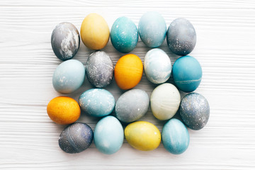 Stylish Easter eggs composition, flat lay on white wooden background. Modern colorful easter eggs painted with natural dye. Happy Easter greeting card. Easter pattern