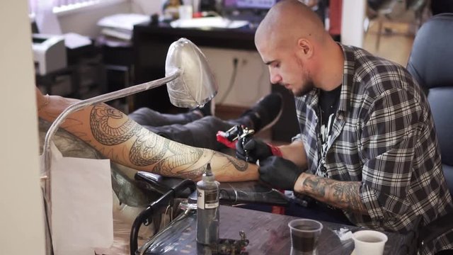 Professional tattoo artist makes tattoo in the salon.