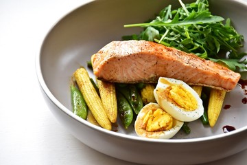 Roasted salmon with stir fry vegetables and egg isolated on white