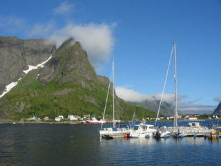 Fototapeta na wymiar Small private Lofoten harbour with sailboat in sunny day with blue sky
