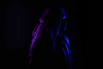 Fototapeta na wymiar beautiful profile girl in the light of neon colored lamps light blue purple contours, girl silhouette. on black background