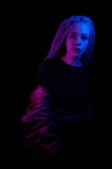 beautiful girl in the light of neon colored lamps light blue purple on black background