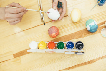 Cropped hands of happy family making various designs on eggs during Easter. Hands are spotted in paint.
