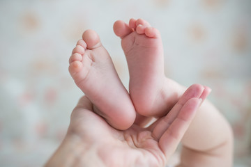 Obraz na płótnie Canvas Newborn baby feet on female hands closeup