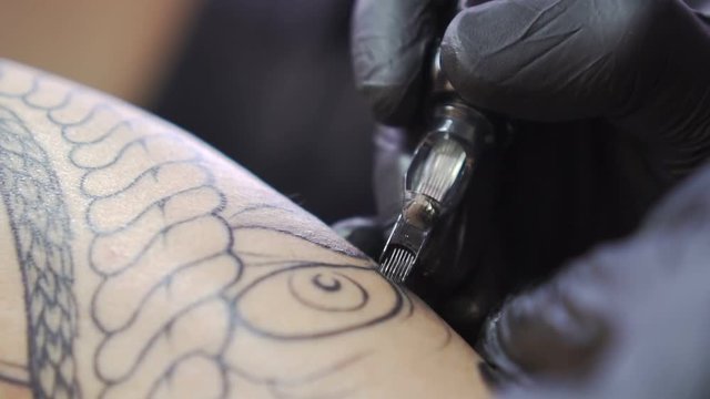 Tattooing, needle pierces the skin, slow motion.