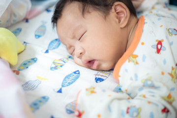 Adorable infant boy sleeping on small bed