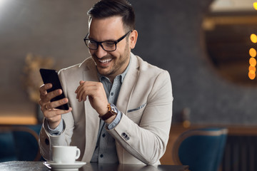 Happy businessman reading a text message on smart phone.