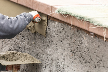 Tile Worker Applying Cement with Trowel at Pool Construction Site